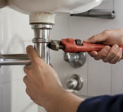 Close-up of a plumber tightening bathroom plumbing pipes during a leak repair service in Shelby Township, Michigan.