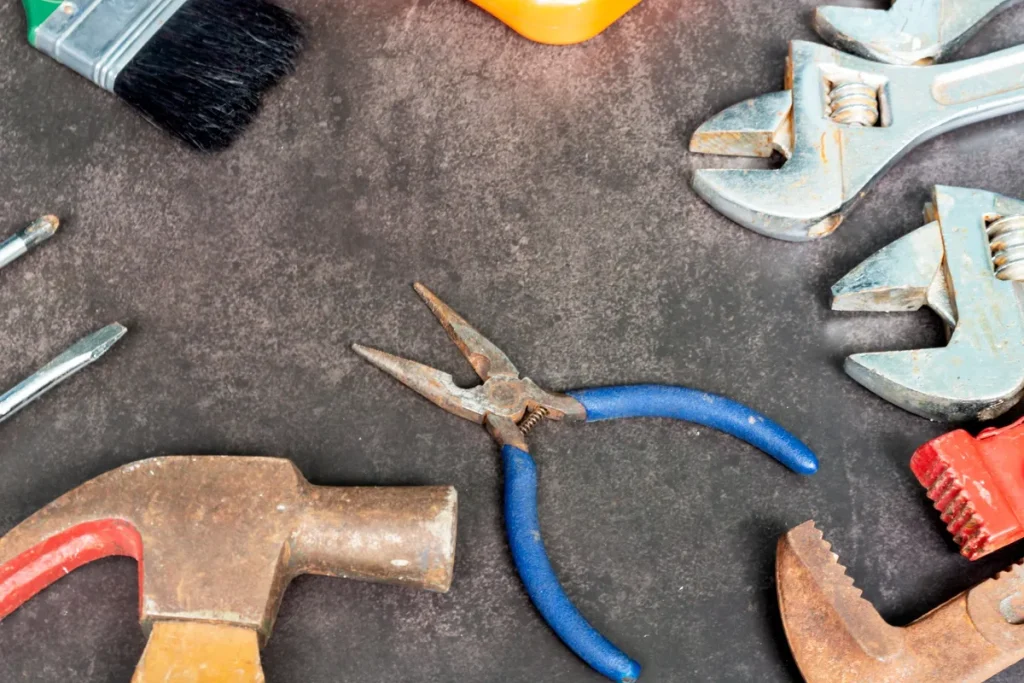 Old plumbing tools scattered on a concrete floor, symbolizing the need for quick repairs in emergencies.