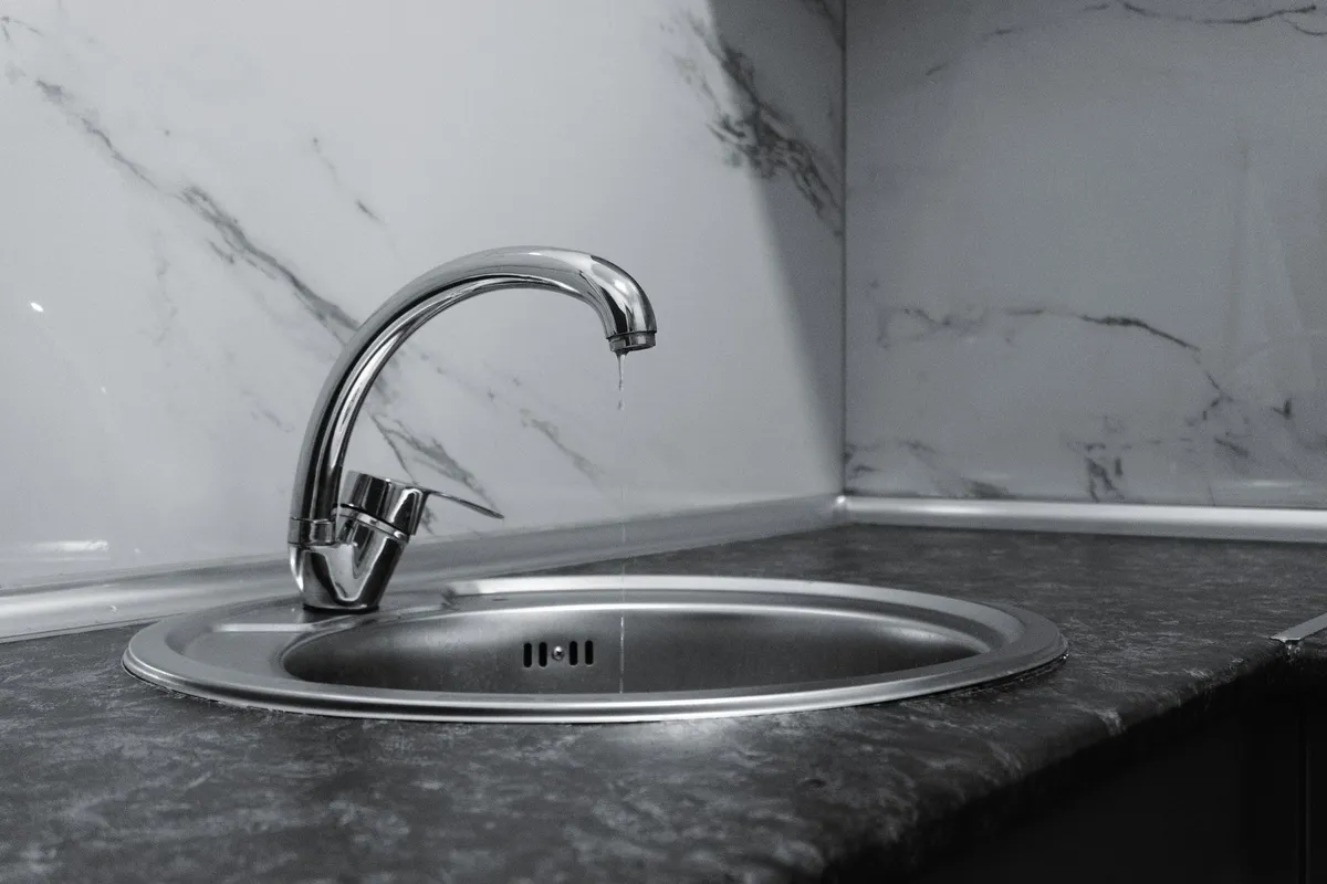 A clean modern kitchen sink with a chrome faucet, emphasizing minimalist design and water conservation.
