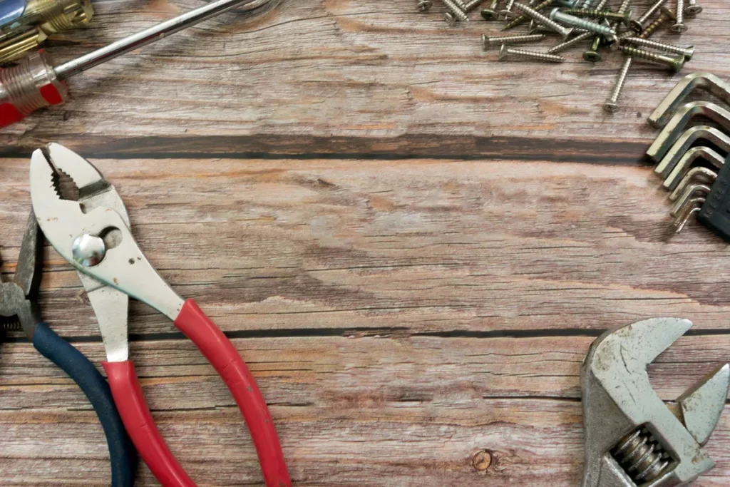 Old plumbing tools scattered on a wooden floor, highlighting the importance of quick repairs.