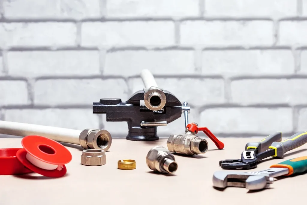 A variety of plumbing tools arranged on a surface, illustrating the theme of plumbing repairs.