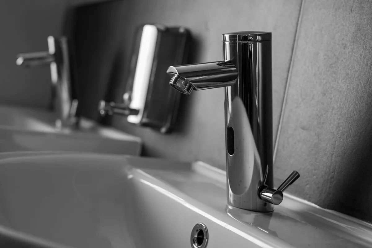 Close-up of a sleek stainless steel faucet over a white sink, highlighting plumbing quality.